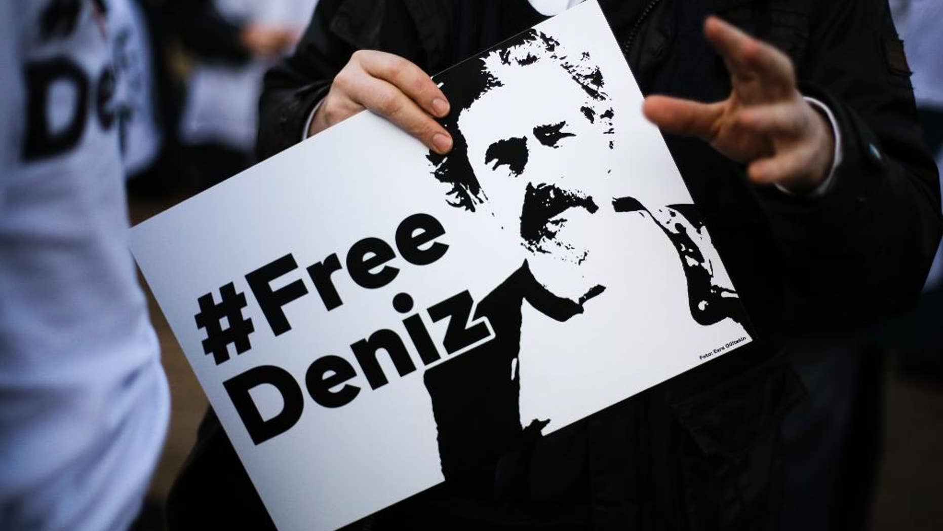 A man holds a poster with the slogan '#FREEDENIZ' during a protest in front of the Turkish embassy in Berlin, Tuesday, Feb. 28, 2017. Demonstrators protest against the police custody of Deniz Yucel, a correspondent in Turkey for the German daily newspaper 'Welt'. (AP Photo/Markus Schreiber)