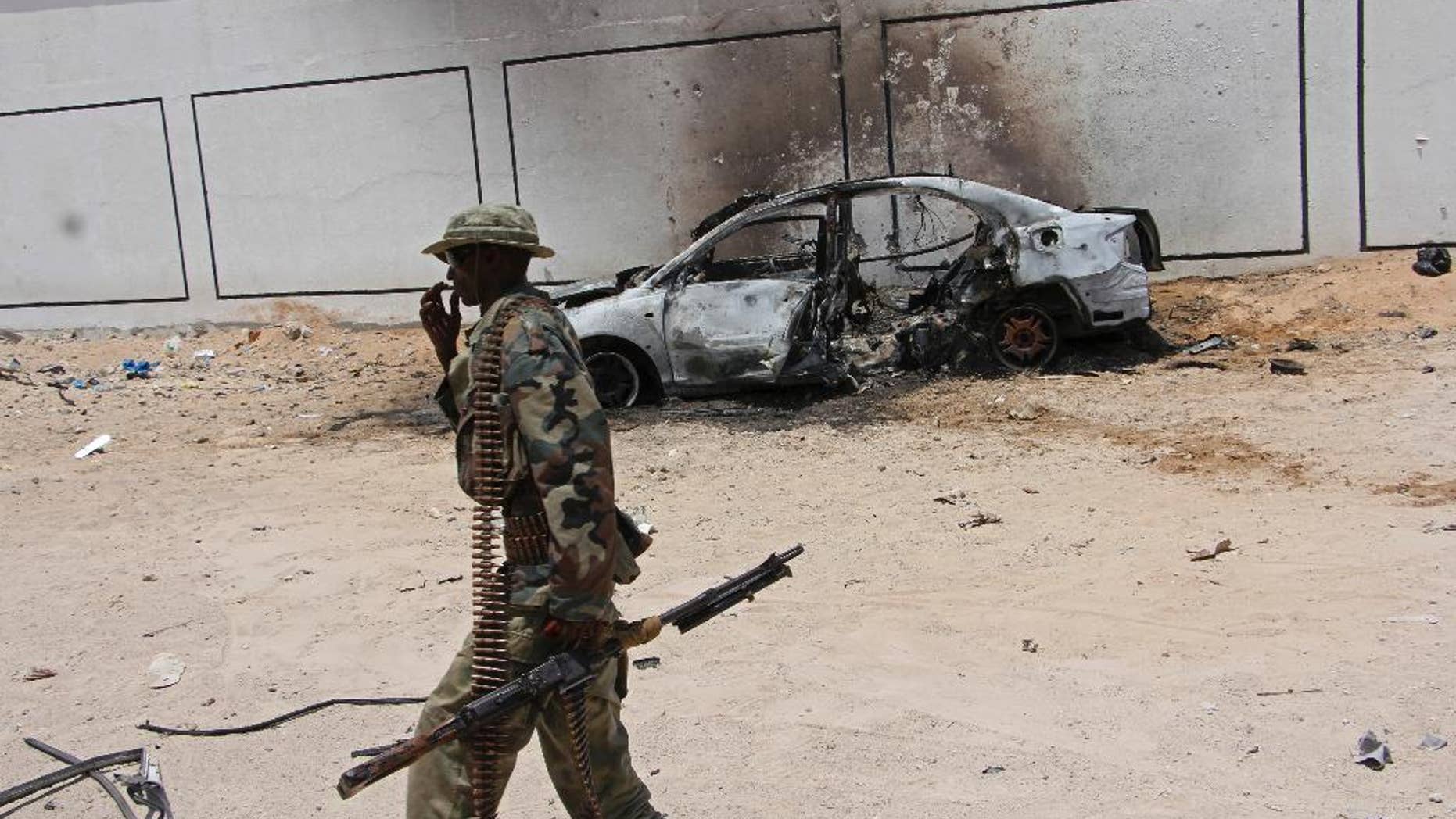 A Somali soldier walks near the wreckage of a car bomb blast near Aden Abdule international airport in Mogadishu, Somalia, Sunday, April, 16, 2017. A Somali police officer says a car bomb detonated near the Somali capital's airport. (AP Photo/Farah Abdi Warsameh)