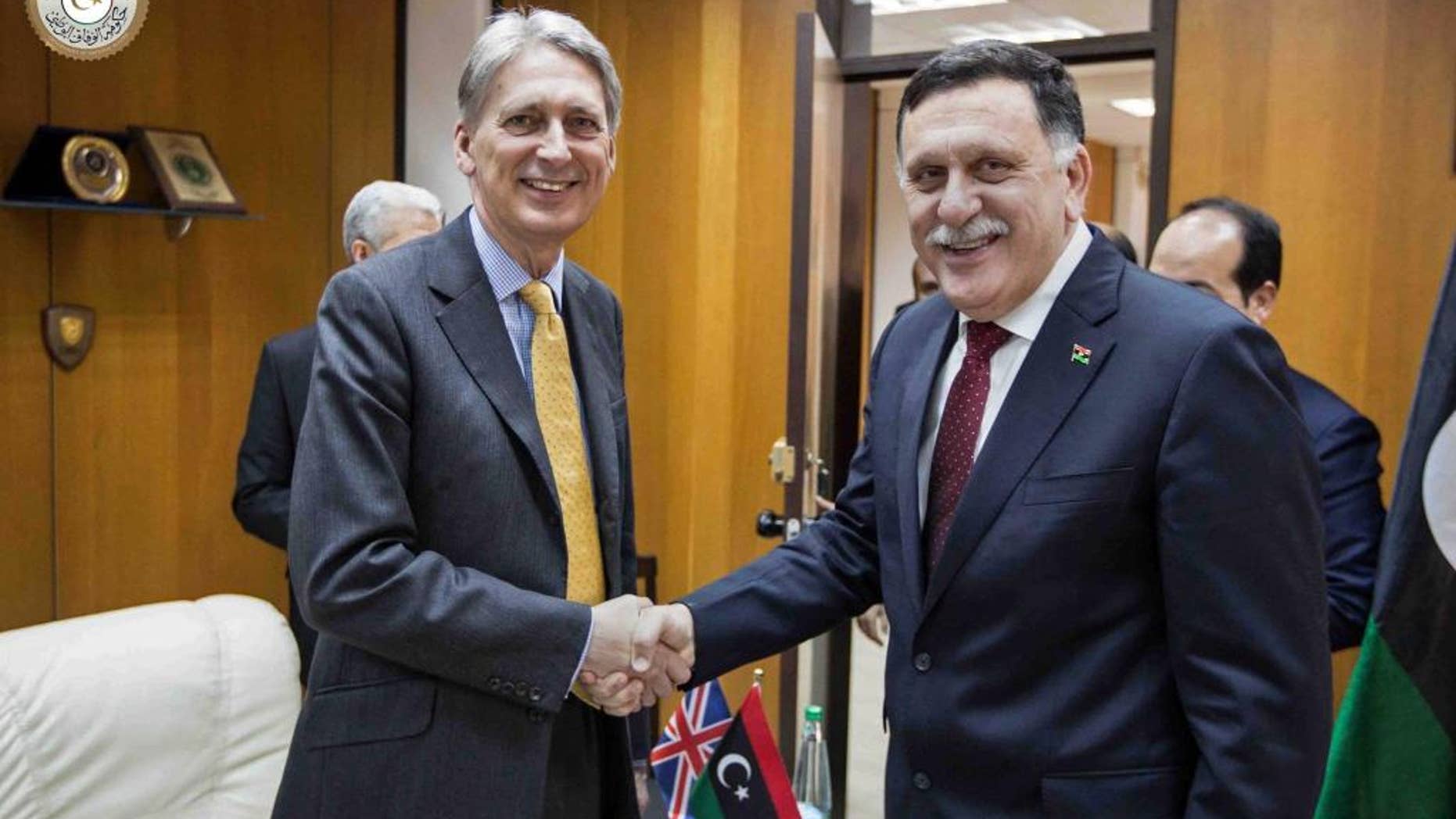In this photo provided by the Libyan Government of National Accord, Libyan prime minister-designate Fayez Serraj , right and British Foreign Secretary Philip Hammond shake hands for photographers in Tripoli, Libya, Monday, April 18, 2016. Western nations hope the U.N.-backed government, known as the Government of National Accord or the GNA, can unite the country in order to combat an increasingly powerful Islamic State affiliate. (Libyan Government of National Accord via AP)
