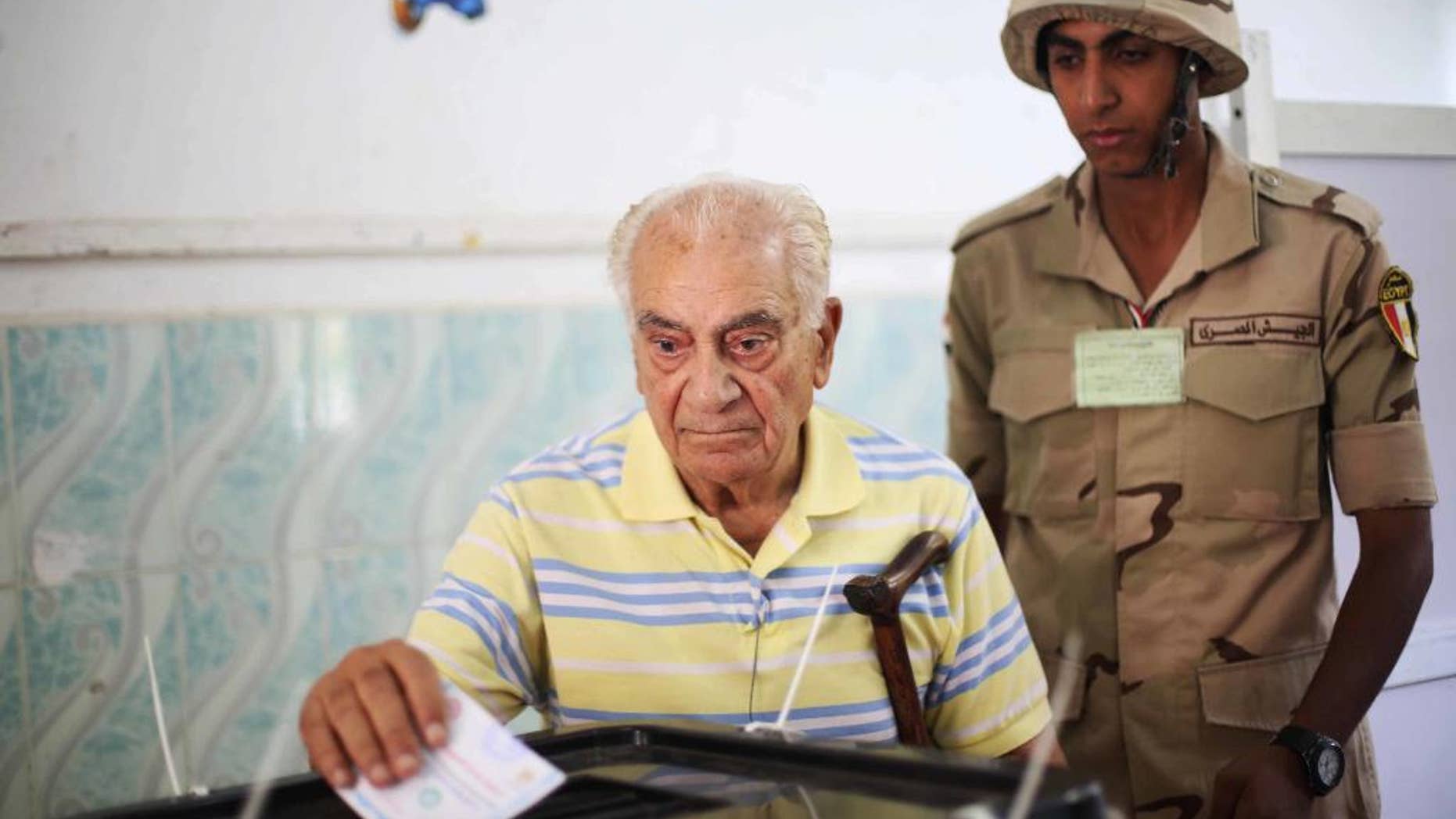 FILE - In this Monday, May 26, 2014 file photo, an Egyptian soldier watches a voter cast his ballot in the presidential election in Cairo, Egypt. A new-old idea is rattling around the Middle East five years after the Arab Spring caused stirrings of democratic ambition: that a restoration of security, especially if accompanied by some economic and political reforms, should be enough for the moment. (AP Photo/Mostafa Elshemy, File)