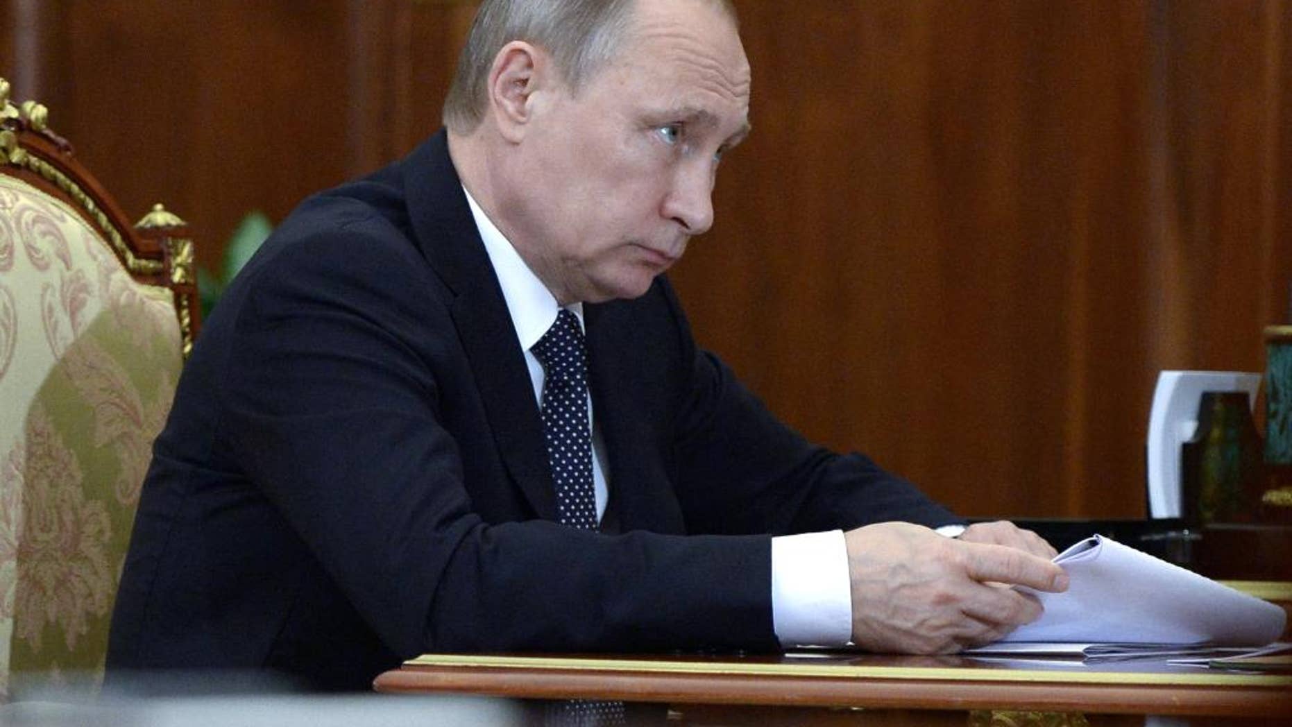 Russian President Vladimir Putin holds papers during a meeting in Moscow's Kremlin on Friday, Aug. 5, 2016. (Alexei Nikolsky/Sputnik, Kremlin Pool Photo via AP)