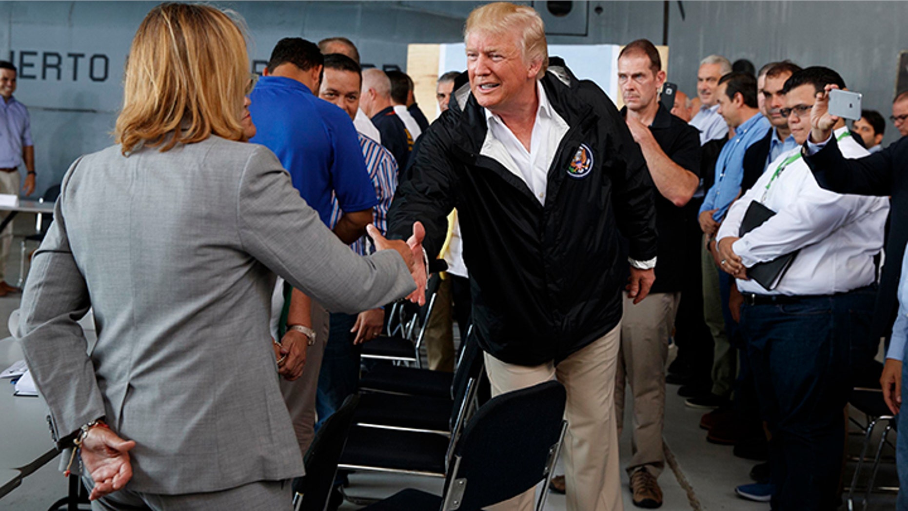 President Donald Trump shakes hands with San Juan Mayor Carmen Yulin Cruz during a briefing on hurricane recovery efforts with first responders at Luis Muniz Air National Guard Base, Tuesday, Oct. 3, 2017, in San Juan, Puerto Rico.