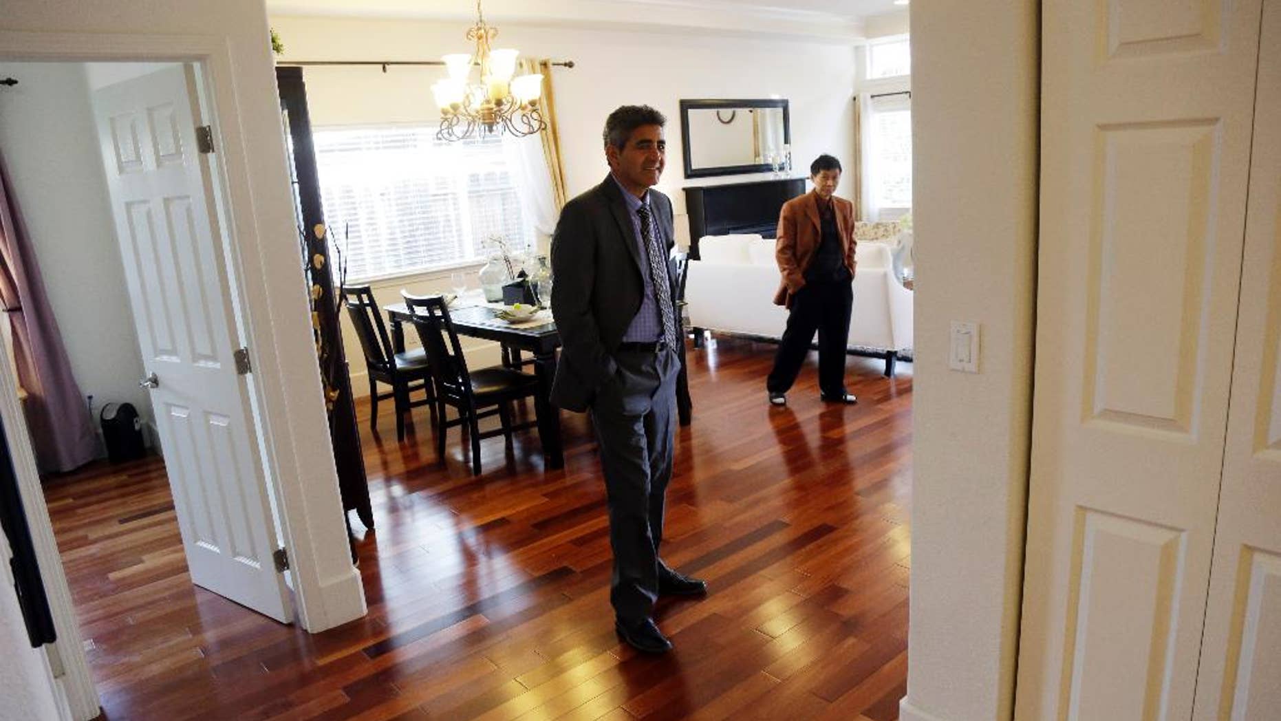 In this Jan. 8, 2015 photo, real estate agent Sam Golkar, left, tours a home being sold by fellow agent Frank Ruan, right, in Cupertino, Calif. The National Association of Realtors reports on sales of existing homes in December on Friday, Jan. 23, 2015. (AP Photo/Marcio Jose Sanchez)