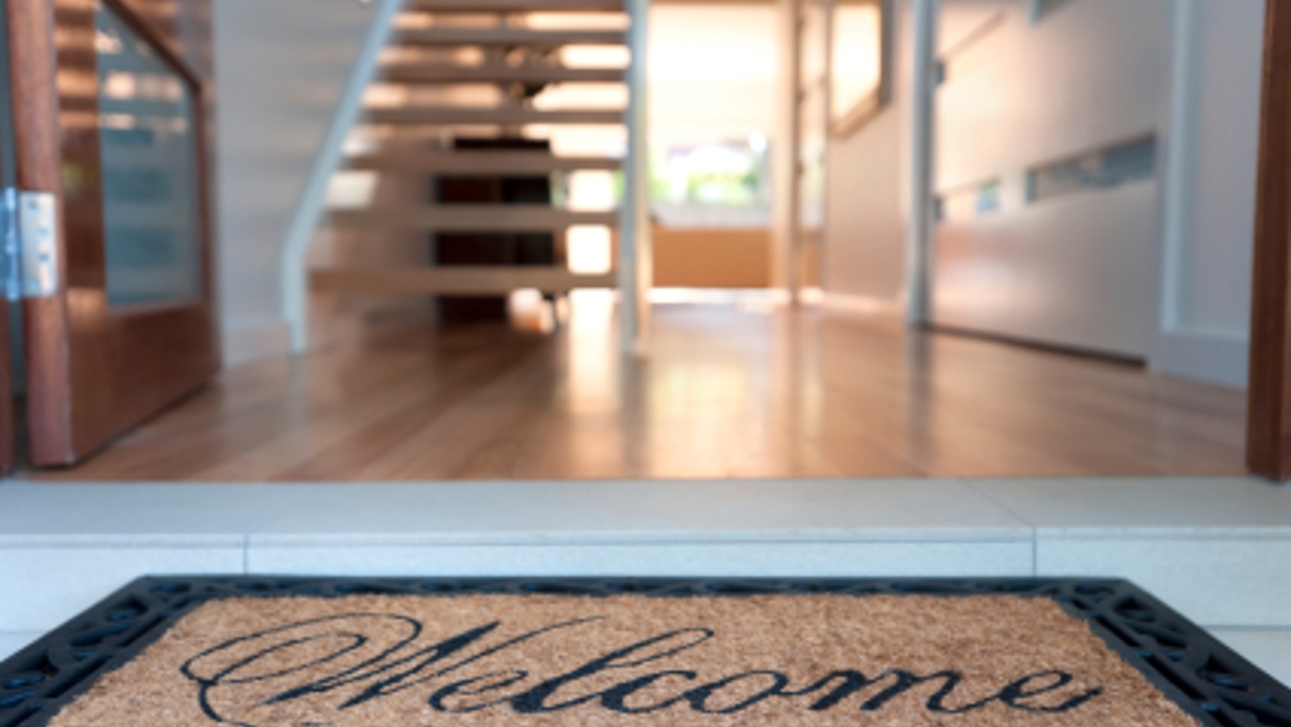 Close up of a welcome mat in front of an inviting house.