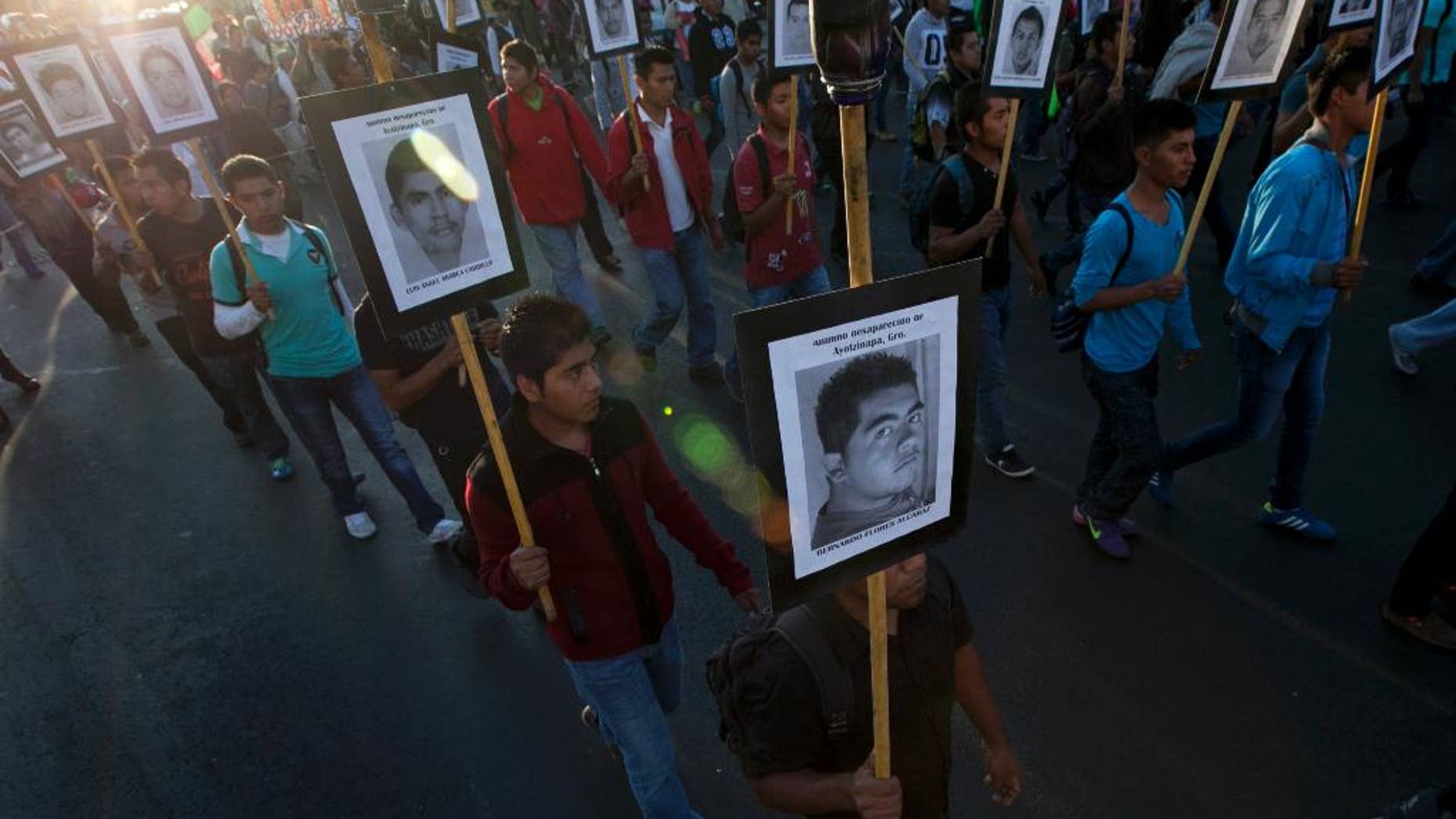 FILE - In this Dec. 26, 2015, file photo, relatives of the 43 missing students from the Isidro Burgos rural teachers college march holding pictures of their missing loved ones during a protest in Mexico City. A third investigation of a dump site in southern Mexico found evidence indicating there was a large fire there in which at least 17 people were burned, a member of a six-person fire expert team said Friday, April 1, 2016. (AP Photo/Marco Ugarte, File)