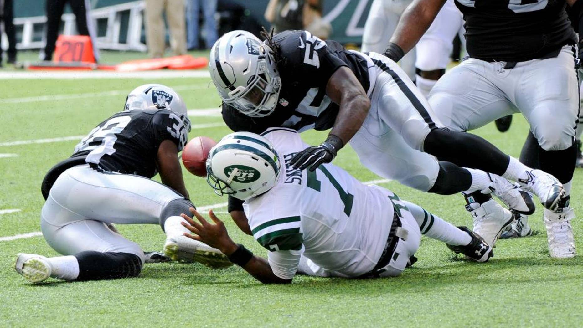 New York Jets' Geno Smith (7) fumbles the ball as he is hit by Oakland Raiders' Sio Moore (55) during the first half of an NFL football game Sunday, Sept. 7, 2014, in East Rutherford, N.J. (AP Photo/Bill Kostroun)