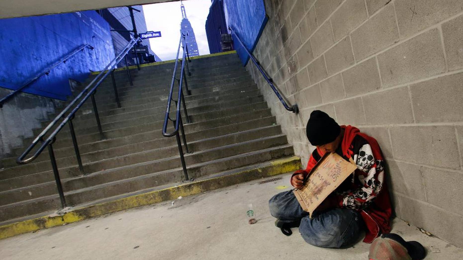 FILE - In this Oct. 9, 2015 file photo, a homeless man holds a sign asking for money while sitting at the entrance to a subway station in New York. New York City plans to deploy hundreds of outreach workers who will canvass much of Manhattan every day with a deceptively simple goal: talk to as many homeless people as possible, as often as possible. Through frequent contact, the city hopes to persuade the chronic homeless, even those living on the street for years, to go to shelters. (AP Photo/Mark Lennihan, File)