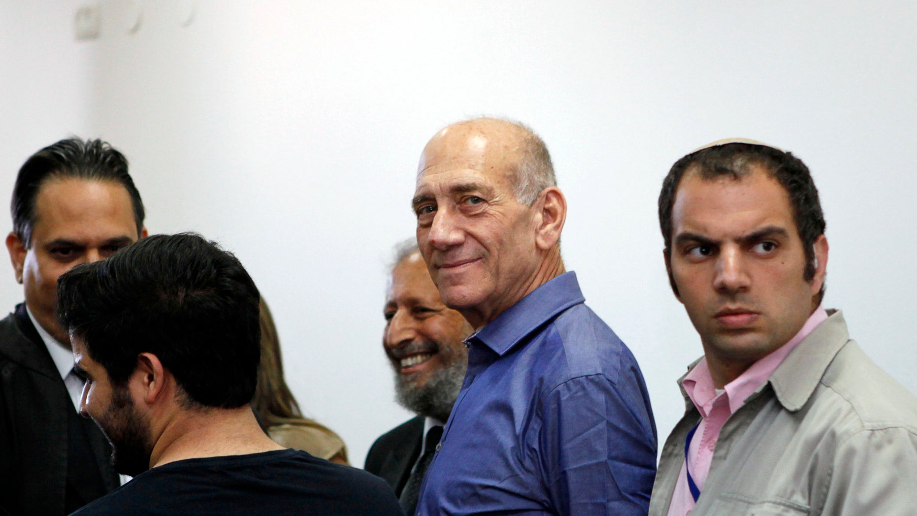 July 10, 2012: Former Israeli Prime Minister Ehud Olmert stands next to lawyers at Jerusalem's District Court following a verdict hearing in his trial.