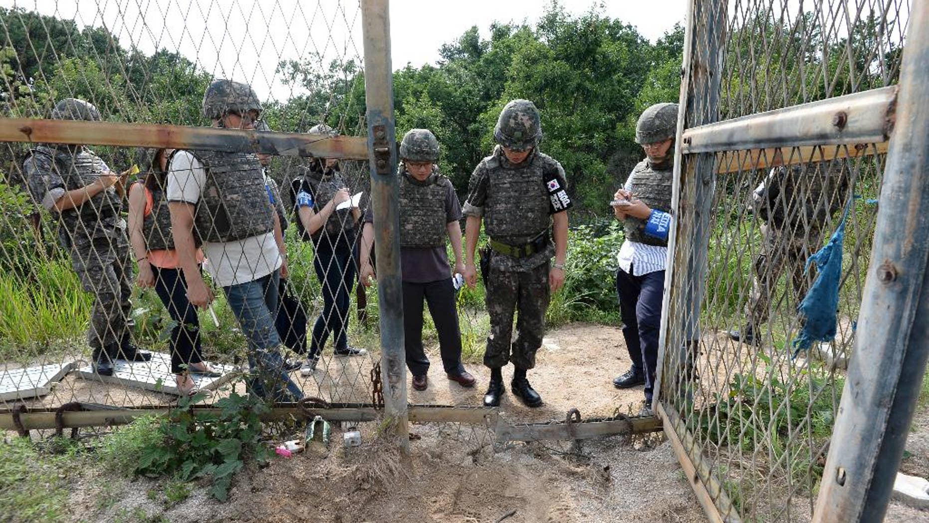 FILE - In this Aug. 9, 2015 file photo provided by the Defense Ministry, an unidentified South Korean army official, second from right, gives a briefing to the media at the scene of a blast inside the demilitarized zone in Paju, South Korea. North Korea insisted Tuesday, Sept. 1, 2015 that its recent expression of “regret” over a mine explosion that maimed two South Korean soldiers was not an apology, as Seoul claims it was. (The Defense Ministry via AP, FIle)