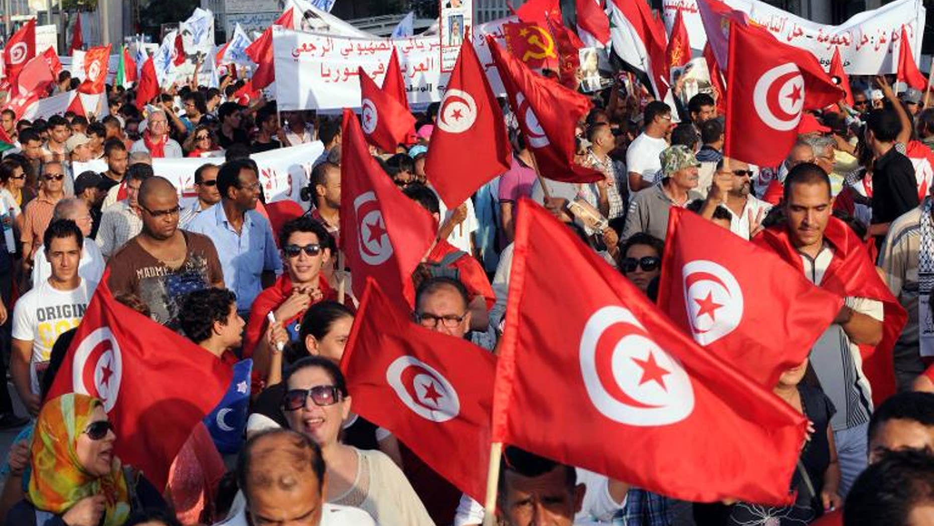 Tunisians wave their national flag as they march outside the National Assembly in Tunis on September 7, 2013, to mark the 40th day since the assassination of opposition politician Mohamed Brahmi.