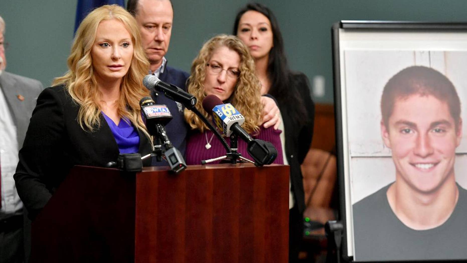 Jim and Evelyn Piazza stand by as Centre County District Attorney Stacy Parks Miller, left, announces the results of an investigation into the death of their son Timothy Piazza, seen in photo at right, a Penn State University fraternity pledge, during a press conference Friday, May 5, 2017, in Bellefonte, Pa. Timothy Piazza had toxic levels of alcohol in his body and was badly injured in a series of falls, authorities said Friday in announcing criminal charges against members of the organization and the frat itself. (Abby Drey/Centre Daily Times via AP)