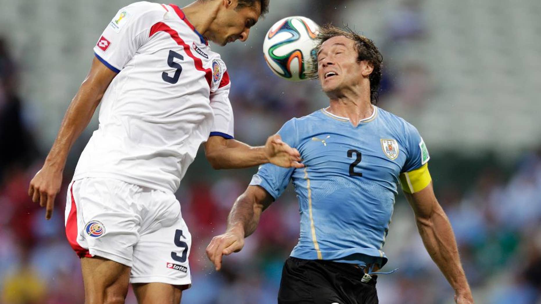 Costa Rica's Celso Borges (5) heads the ball past Uruguay's Diego Lugano (2) during the group D World Cup soccer match between Uruguay and Costa Rica at the Arena Castelao in Fortaleza, Brazil, Saturday, June 14, 2014. (AP Photo/Fernando Llano)