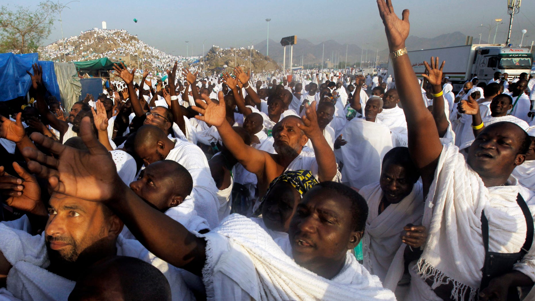 FILE - In this Monday, Oct. 14, 2013 file photo, Muslim pilgrims raise their hands to receive umbrellas in front of a rocky hill called the Mountain of Mercy, on the Plain of Arafat near the holy city of Mecca. Some pilgrims who go to Saudi Arabia to perform pilgrimage stay on illegally in the kingdom in search of work. Saudi authorities are launching intensive nationwide security sweeps on businesses and setting up checkpoints in efforts to detain and deport an estimated 1.5 million foreign workers without proper documentation. The crackdown reflects wider efforts by the kingdom to clear out slums and create jobs for its local workforce as leaders worry that rising unemployment could feed dissent and challenges to their rule by their own people. (AP Photo/Amr Nabil)