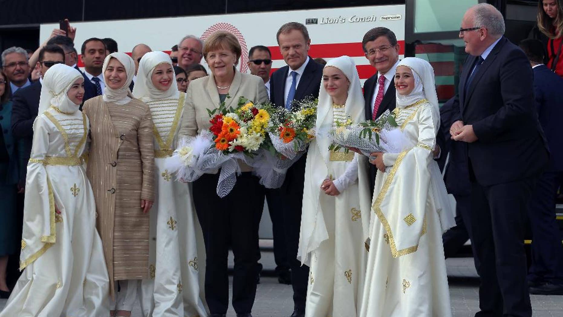 German Chancellor Angela Merkel, center-left, EU Council President Donald Tusk, center-right, Turkish Prime Minister Ahmet Davutoglu, second right, and EU Commission Vice President Frans Timmermans, right, are greeted by Syrian refugee children at a Syrian refugee camp in Nizip, Gaziantep, Turkey, Saturday, April 23, 2016. Merkel and top European Union officials, under pressure to reassess a migrant deportation deal with Turkey, were traveling close to Turkey's border with Syria on Saturday in a bid to bolster the troubled agreement. Davutoglu's wife Sare Davutoglu is at the left. (Hakan Goktepe/Pool Photo via AP)