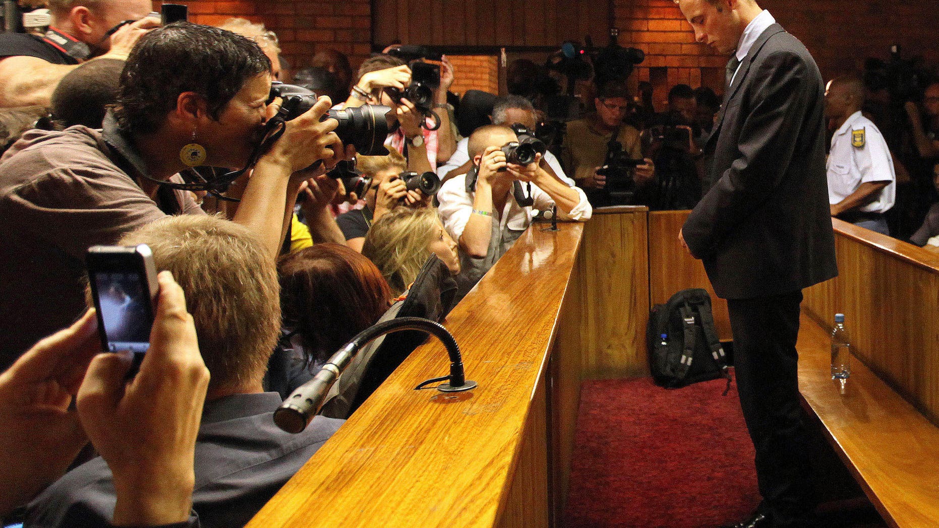 File - In this Wednesday, Feb. 20, 2013 file photo Olympic athlete Oscar Pistorius stands inside a court during his bail hearing at the magistrate court in Pretoria, South Africa. Pistorius will defend himself March 3, 2014 against a charge of premeditated murder in the slaying of his girlfriend Reeva Steenkamp. A South Africa judge has ruled that television stations can broadcast parts of the trial live, but with restrictions on witness testimonies. (AP Photo/Themba Hadebe, File)