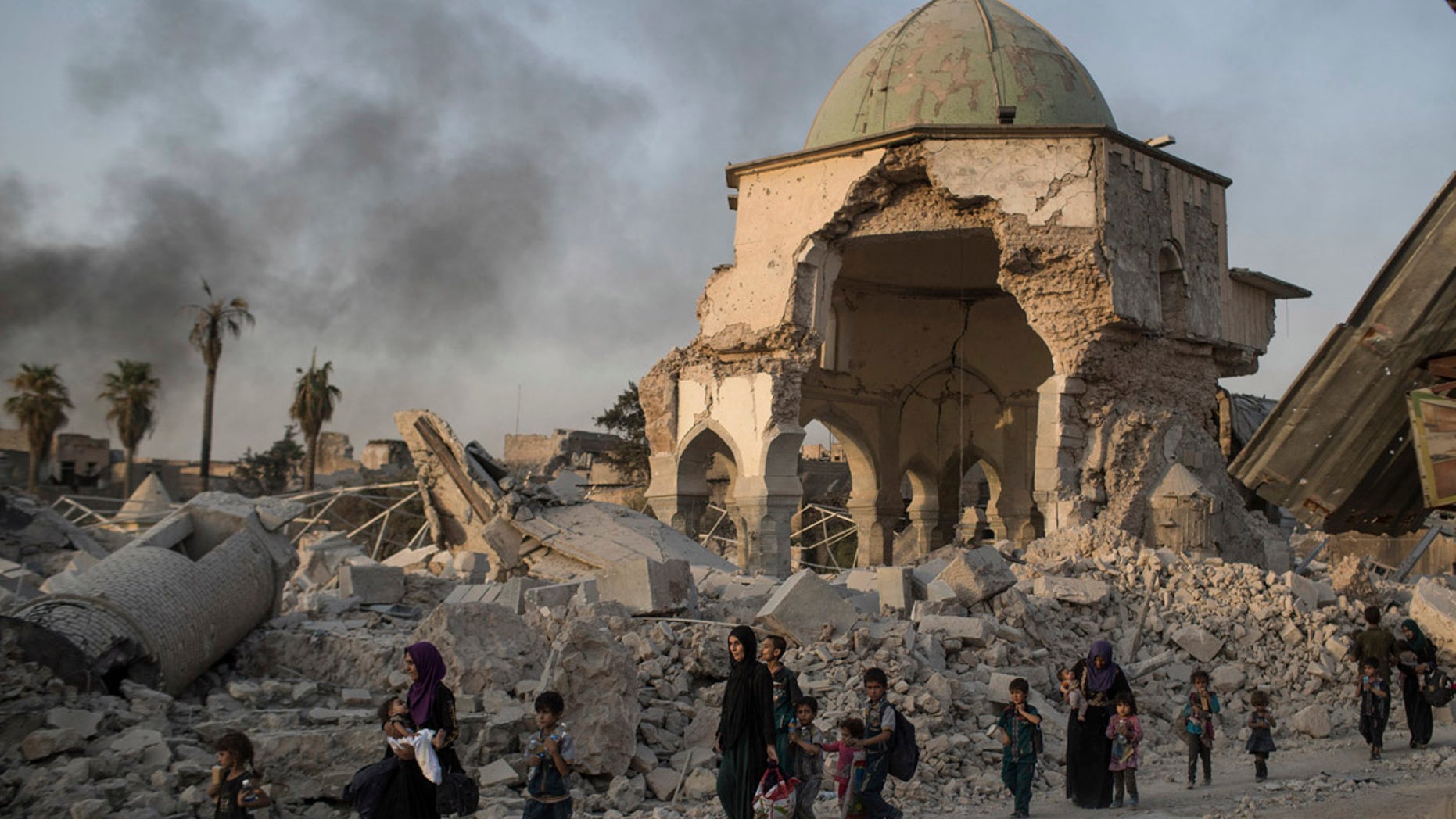 Fleeing Iraqi civilians walk past a heavily damaged al-Nuri mosque as Iraqi forces continue their advance against the Islamic State in this July 4, 2017 file photo.