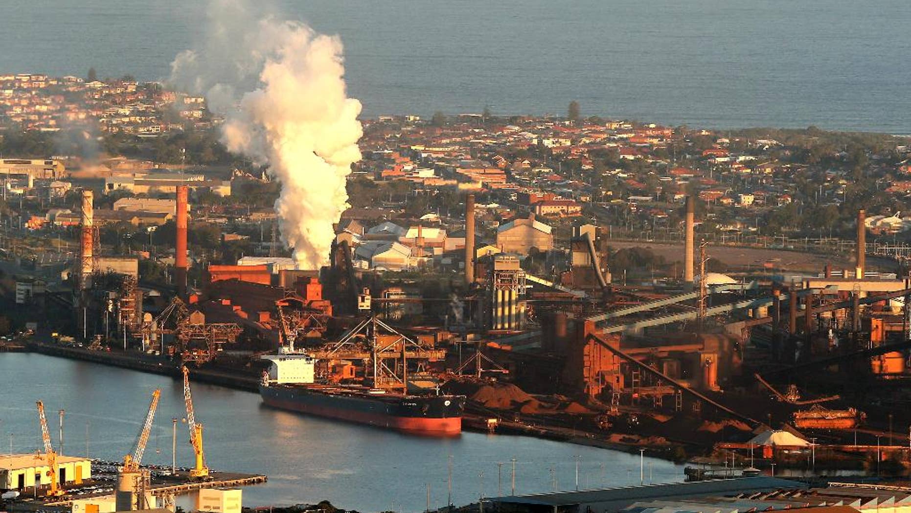 FILE - In this July 2, 2014 file photo, smoke billows out of a chimney stack of BHP steelwork factories at Port Kembla, south of Sydney, Australia. The world's biggest miner, BHP Billiton, on Tuesday, Aug. 16, 2016, reported a $6.4 billion loss, the worst full-year result in the Anglo-Australian company's history. BHP said the result for the fiscal year ending June 30 came from a 31 percent fall in revenue to $30.1 billion amid weak commodity prices, write downs of U.S. oil and gas assets and a disaster at a Brazilian mining joint venture. (AP Photo/Rob Griffith, File)