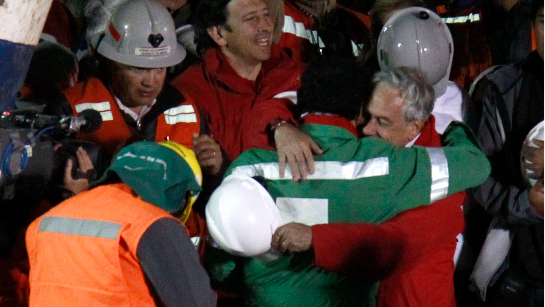 The last rescued miner, Luis Urzua, center wearing green, hugs Chile's President Sebastian Pinera after being rescued from the collapsed San Jose gold and copper mine where he had been trapped with 32 other miners for over two months near Copiapo, Chile, Wednesday Oct. 13, 2010. The 69-day underground ordeal reached its end Wednesday night after 33 trapped miners were hauled up in a cage through a narrow hole drilled through 2,000 feet of rock. (AP Photo/Roberto Candia)