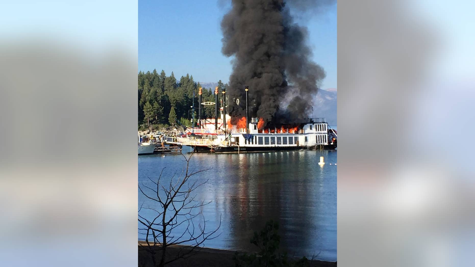 A fire rips through the second deck of a docked tourist cruise boat under repair at Lake Tahoe, in Reno, Nev., Tuesday, Aug. 16, 2016. The fire severely damaged the popular paddle wheeler and injuring two workers on board before crews extinguished the flames that sent a plume of black smoke high above the Sierra waters. (Zach Hastie via AP)