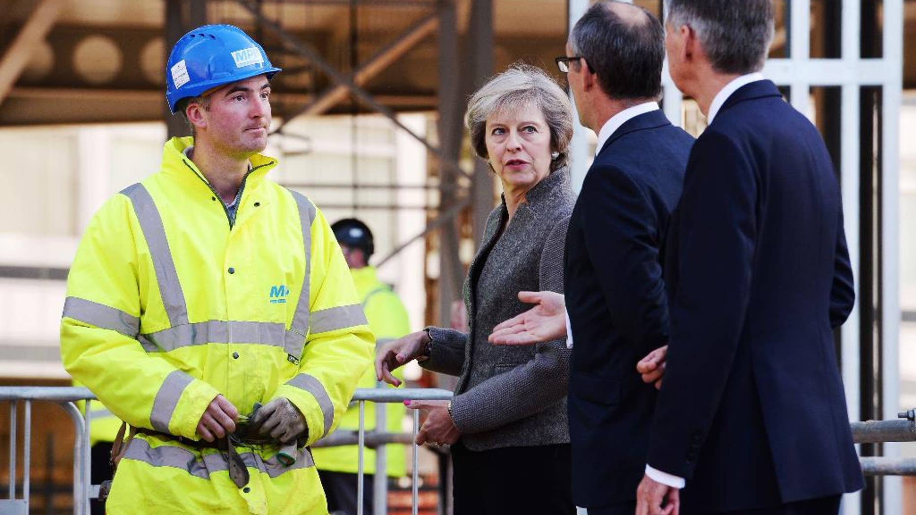 Britain's Prime Minister Theresa May and Chancellor of the Exchequer Philip Hammond, right, during a visit to a construction site in Birmingham, England, where new HSBC bank offices are being built, Monday Oct. 3, 2016. May announced Sunday a timetable for Britain's exit from the European Union, and Treasury chief Hammond warned on Monday of turbulence in the coming years as Britain negotiates its exit from the trading bloc. (Stefan Rousseau / PA via AP)