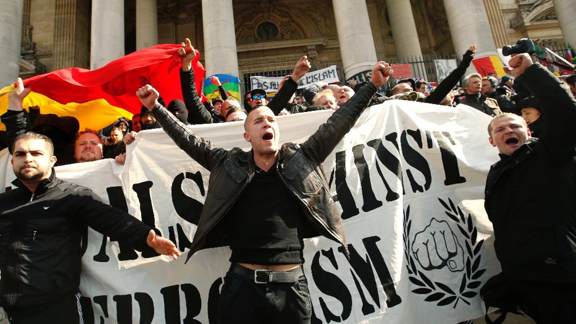 FILE - In this Sunday, March, 27, 2016 file photo, right-wing demonstrators chant slogans next to one of the memorials to the victims of the recent Brussels attacks, at the Place de la Bourse in Brussels. As extreme-right groups threaten to take Molenbeek neighborhood by storm Saturday, April 2, community leaders fear its predominantly Muslim young people will fight back. “They don’t trust the police and they aren’t going to take it,” said Fouad Ben Abdelkader, a teacher in the neighborhood. On Thursday he joined a meeting of a couple dozen community leaders and mentors to neighborhood youths who feel adrift in mainstream Belgian society. The group of community organizers was looking for ways to head off an escalation of violence in the largely Muslim neighborhood, hoping to avoid a situation like occurred last Sunday when hundreds of black-clad hooligans shouting Nazi slogans disrupted a memorial at Brussels’ Bourse square for the 32 victims of the March 22 attacks on the airport and subway system. (AP Photo/Alastair Grant, file)