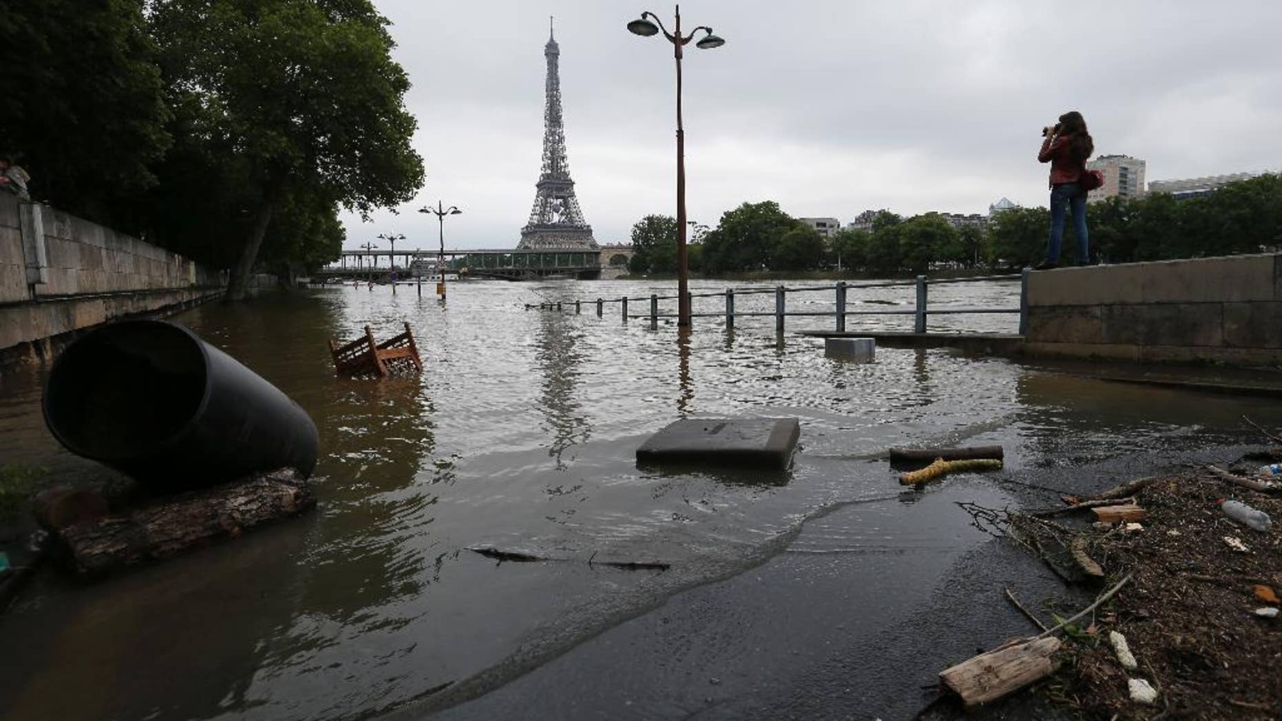 A woman takes photos of the flooded banks of the Seine river in Paris, France Saturday June 4, 2016. The level of the Seine started to drop after peaking earlier in the morning. Both the Louvre and Orsay museums were closed as officials said the Seine had been at its highest level in nearly 35 years. (AP Photo/Francois Mori)