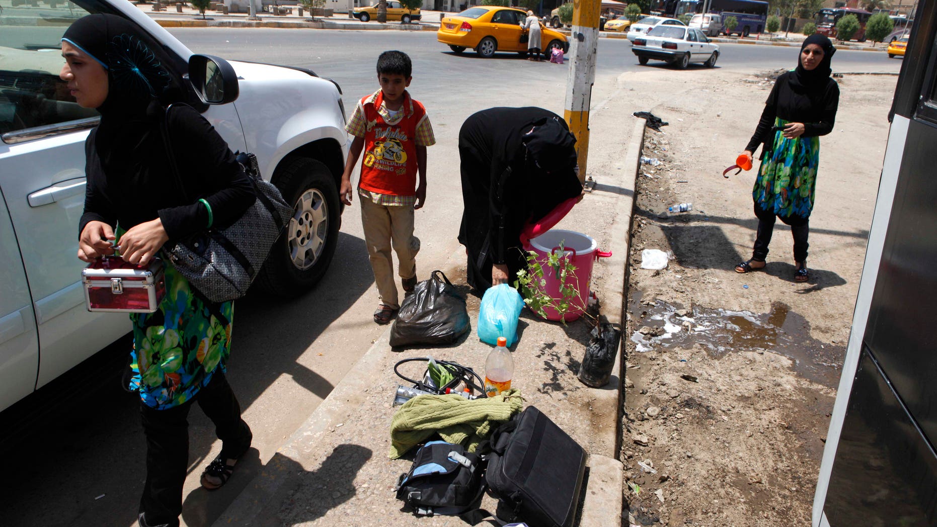 July 20. 2012: Iraqi refugees who have just returned from Syria unload their luggage from a bus in the Mansour neighborhood of Baghdad, Iraq.