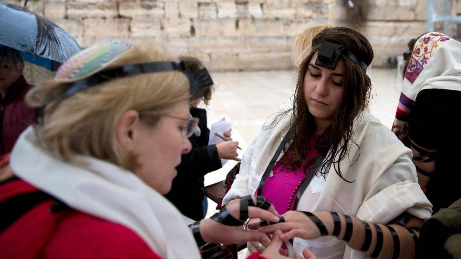 FILE - In this Sunday, Feb. 7, 2016 file photo, Israeli women put on Tefillin also known as Phylacteries, a small leather box containing religious text usually worn by Jewish men, at the Western Wall, the holiest site where Jews can pray in Jerusalem's Old City. Israel's attorney general has banned Jewish women's prayer group called Women of the Wall from holding an all-female "priestly blessing" next week and it is an unrecognized custom that has never been held at the Western Wall. (AP Photo/Sebastian Scheiner, File)
