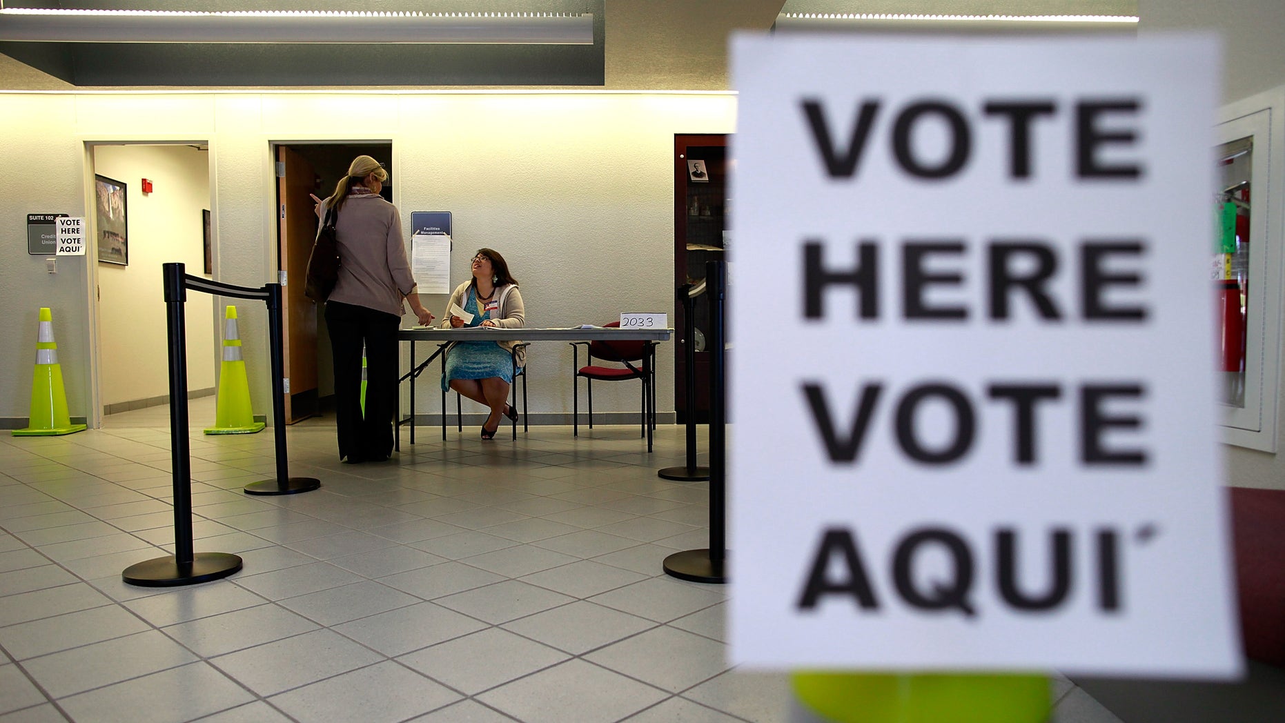 MANSFIELD, TX - NOVEMBER 06: An election official answers a question for a voter on November 6, 2012 in Mansfield, Texas. Americans across the country participate in Election Day as President Barack Obama and Republican nominee former Massachusetts Gov. Mitt Romney remain in a virtual tie in the national exit polls. (Photo by Tom Pennington/Getty Images)