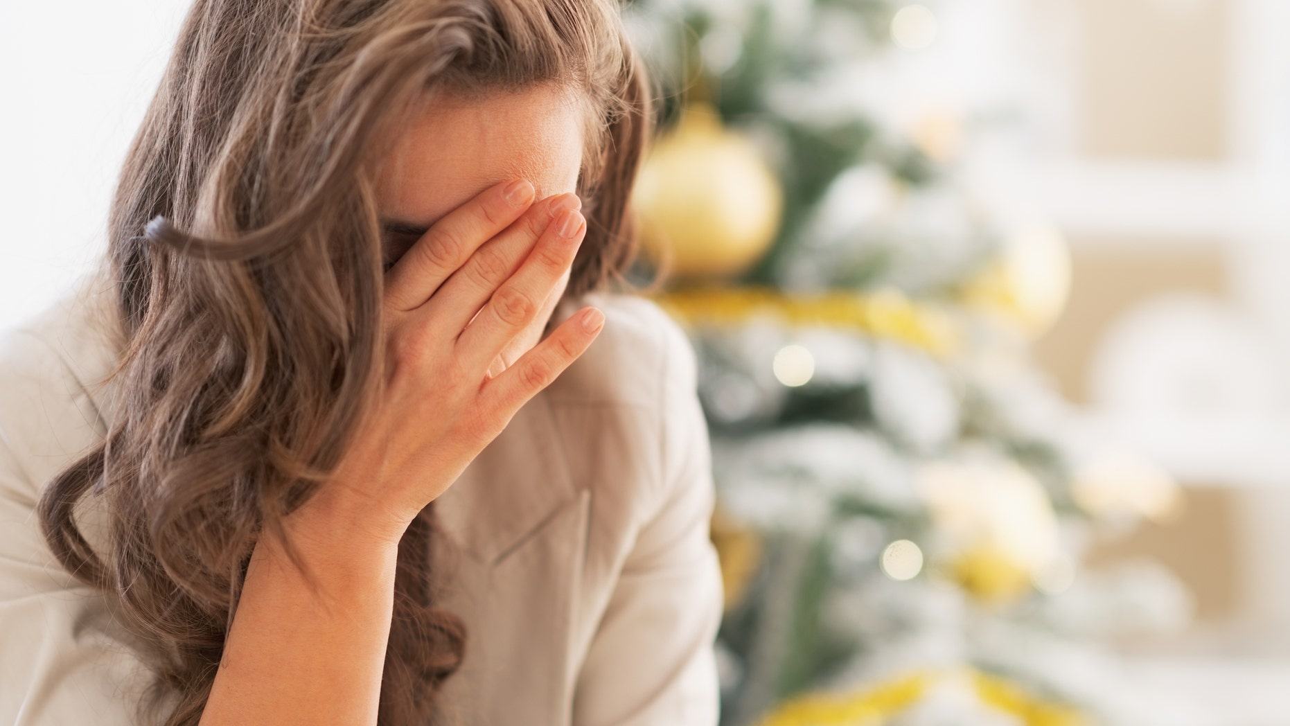 Stressed young woman in front of christmas tree