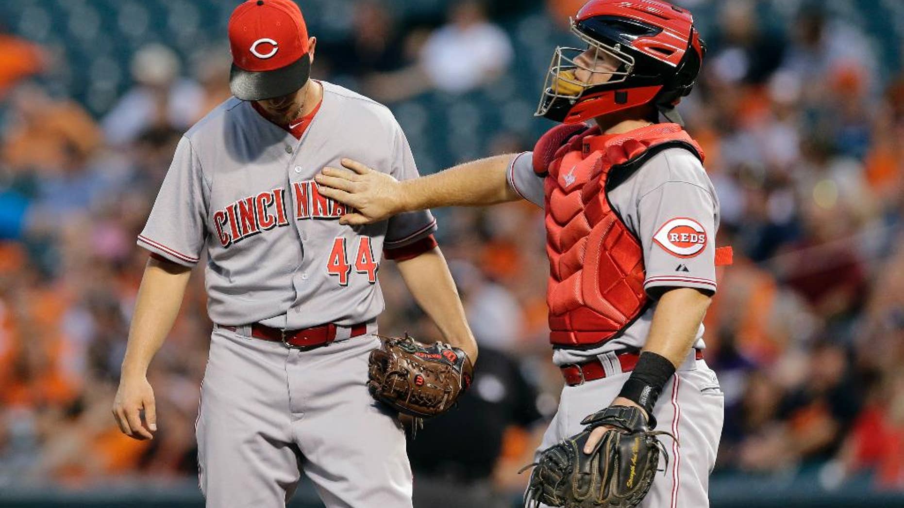 Cincinnati Reds catcher Tucker Barnhart, right, pats starting pitcher Mike Leake on the chest during a visit to the mound after Leake walked Baltimore Orioles' J.J. Hardy in the first inning of an interleague baseball game, Thursday, Sept. 4, 2014, in Baltimore. Baltimore scored six runs in the first. (AP Photo/Patrick Semansky)