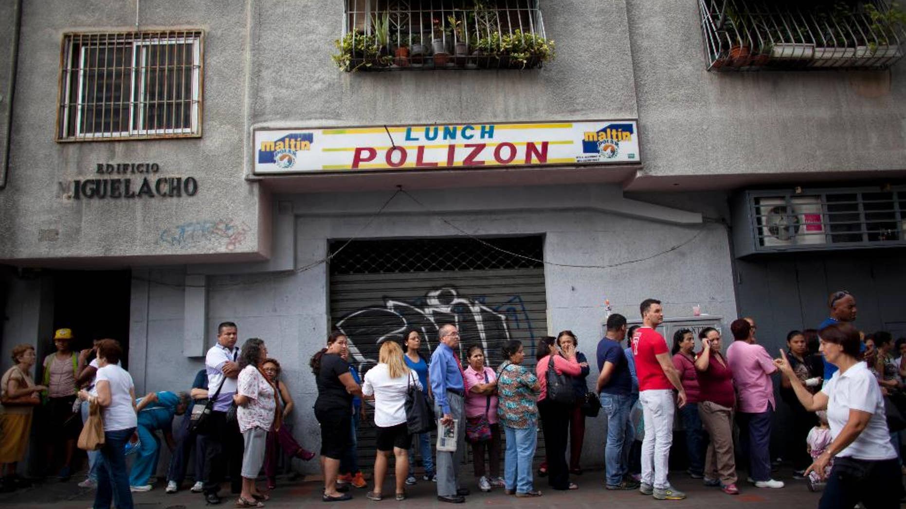 FILE - In this Oct. 23, 2014 file photo, people wait in line to enter a small market to try to buy hard to find items like disposable diapers, laundry detergent and razors in downtown Caracas, Venezuela. President Nicolas Maduro announced Friday, Oct. 31 he is deploying hundreds of inspectors to enforce the government's price regulations on retailers. (AP Photo/Ariana Cubillos, File)