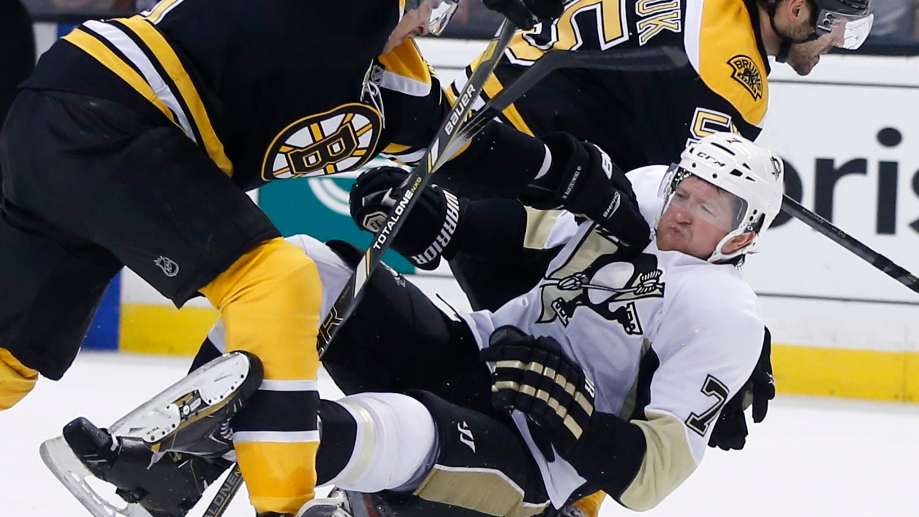 Pittsburgh Penguins defenseman Paul Martin (7) is knocked down by Boston Bruins defensemen Matt Bartkowski, left, and Johnny Boychuk (55) in the third period of an NHL hockey game in Boston, Monday, Nov. 25, 2013. The Bruins won 4-3 in overtime. (AP Photo/Elise Amendola)
