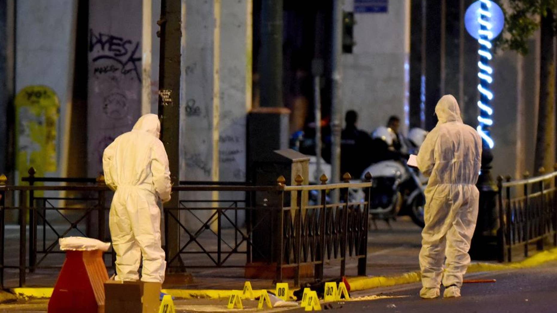 Members of the bomb squad search for evidence outside Labor Ministry in Athens early Monday, Dec. 12, 2016. Greek authorities have destroyed a time bomb planted overnight outside the Labor Ministry on a major thoroughfare in central Athens, after a warning telephone call was made to a newspaper, police said Monday. No injuries or damage were reported. (Antonis Nikolopoulos/Eurokinissi via AP)