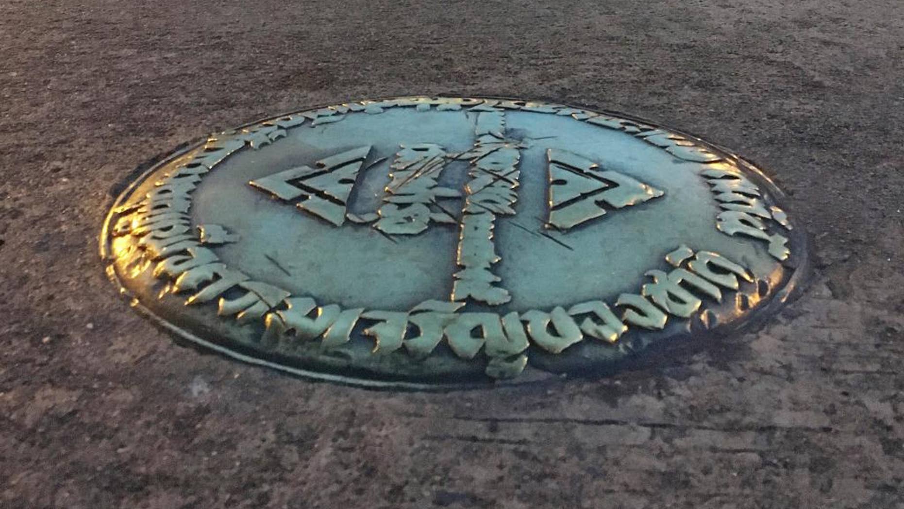 FILE - In this Oct. 2, 2016, file photo, a small bronze plaque commemorating Thailand's 1932 revolution rests in the pavement of the Royal Plaza in Bangkok, Thailand. In early April, the plaque was mysteriously removed by parties unknown and substituted by one praising the Chakri Dynasty, whose 10th king took the throne last December. The Foreign Correspondents' Club of Thailand has accepted a police request that it cancel a panel discussion on the mysterious theft of a plaque commemorating the end the country's absolute monarchy in 1932. (AP Photo/Apichart Khunnawatbandit)