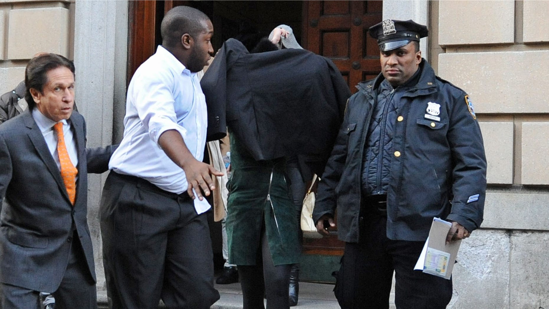 Nov. 29, 2012: Lindsay Lohan, second from right, is escorted from the 10th Precinct police station, with her face shielded in New York after being charged for allegedly striking a woman at a nightclub.