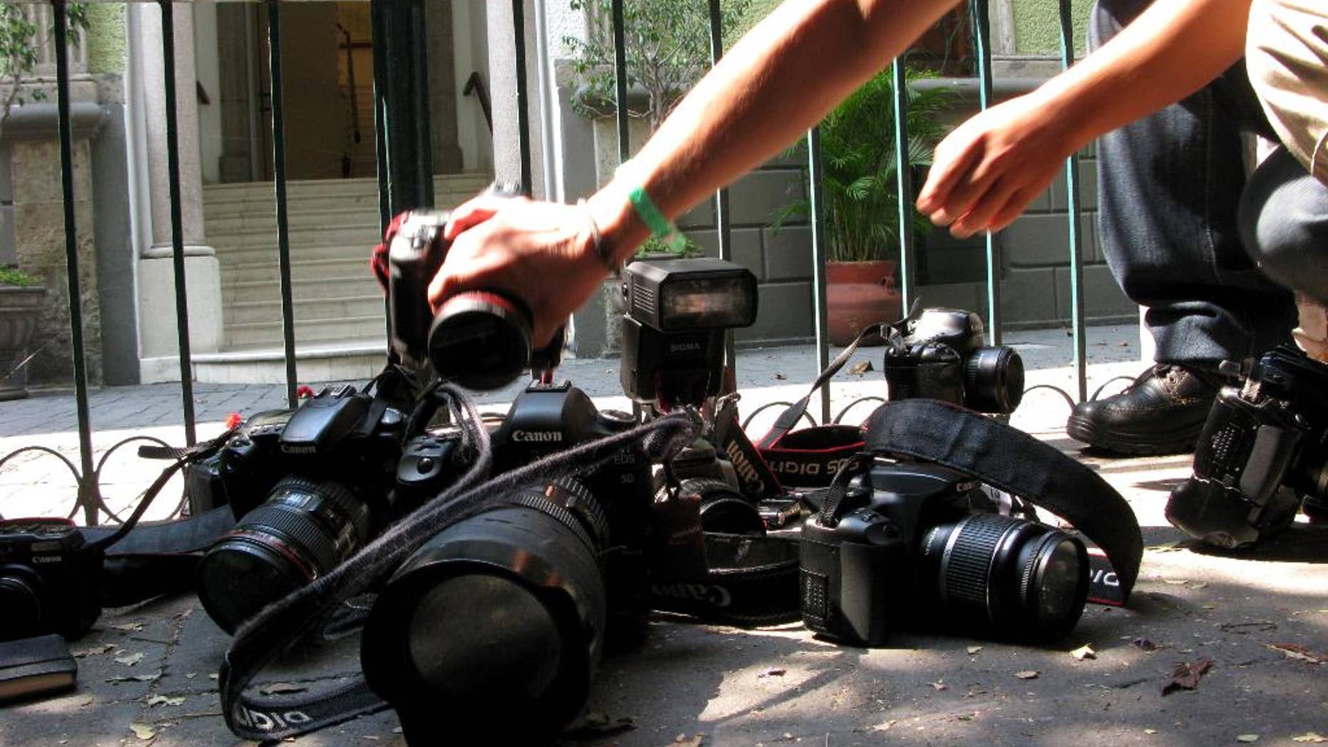 FILE - In this April 29, 2012, file photo, photojournalists place their cameras on the ground during a demonstration in Mexico City condemning the alleged murder of fellow journalist Regina Martinez, a correspondent for the Mexican investigative magazine Proceso. Ruben Espinosa, a photographer who worked for Proceso and other media, was among five people found slain early Saturday, Aug. 1, 2015, in an apartment in Mexico City, according to the magazine. He had recently gone into self-exile from the Gulf coast state of Veracruz, where he felt under threat, the magazine added. According to the Committee to Protect Journalists, 11 journalists have been killed in Veracuz since 2010, the most recent just a month ago. Two others, including Espinosa, were Veracruz journalists found dead outside of the state. (AP Photo/Marco Ugarte, File)