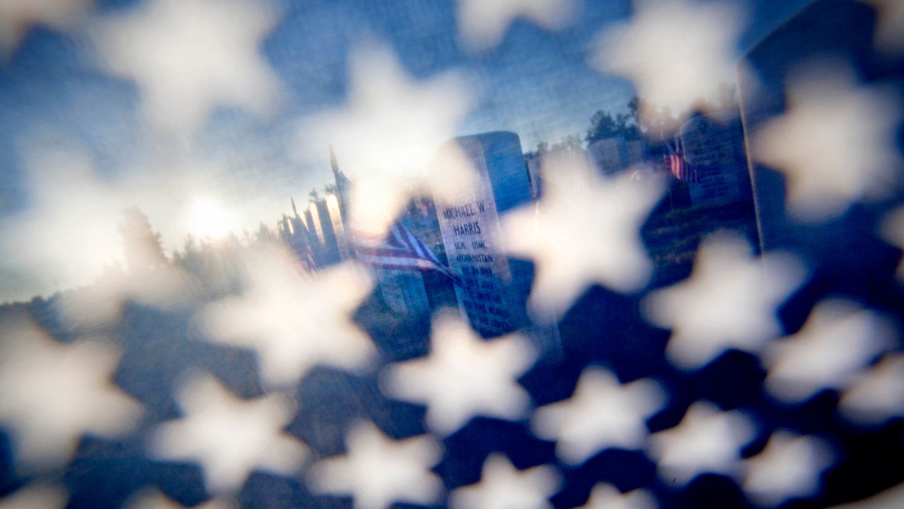 The grave of U.S. Marine Lance Cpl. Michael Harris is seen through an American flag as the the sun rises over Georgia National Cemetery Monday, May 28, 2012, in Canton, Ga. Harris died Feb. 6, 2012, in North Carolina. (AP Photo/David Goldman)