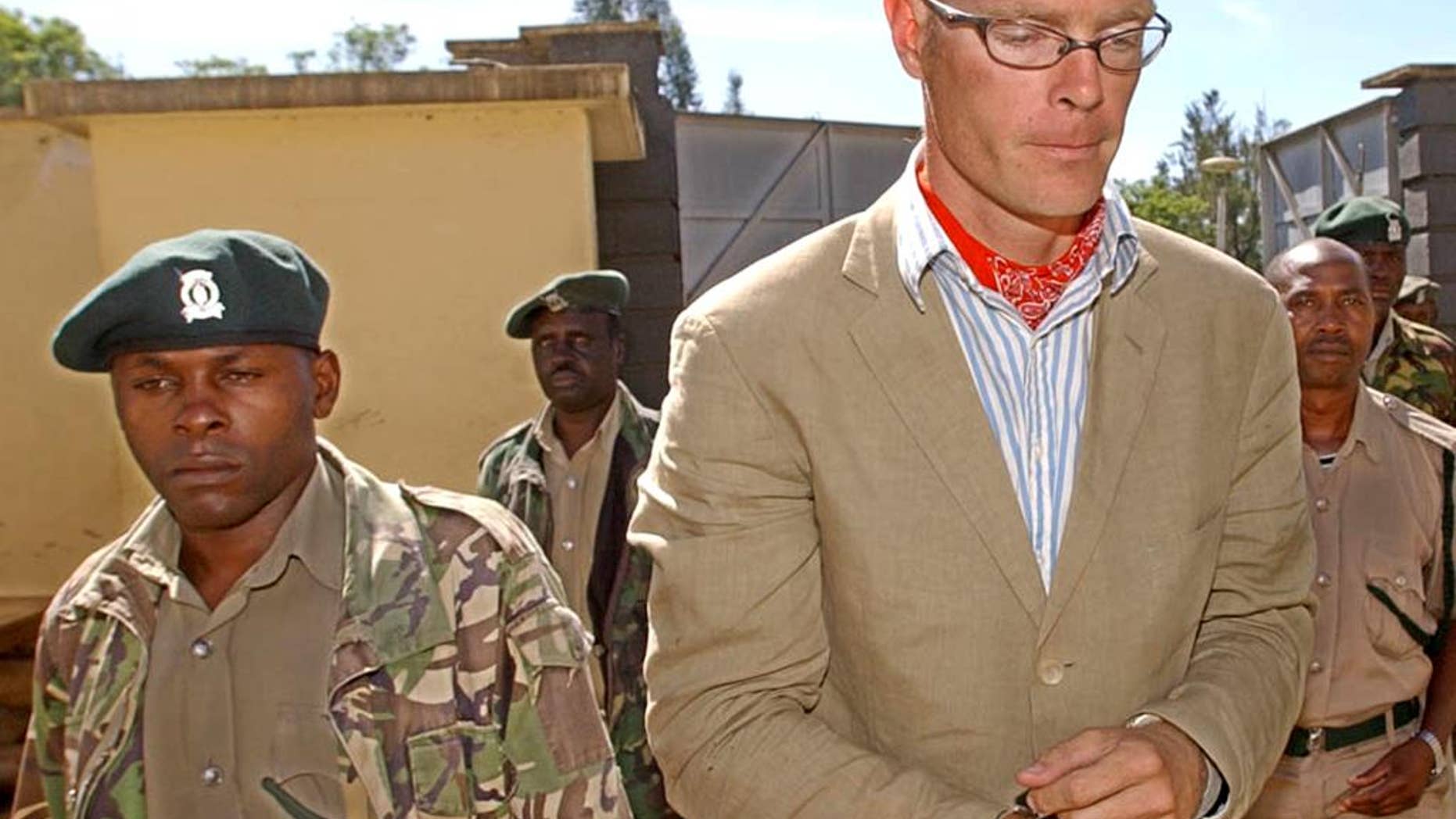 FILE---In this file photo of May 18, 2005, Thomas Patrick Gilbert Cholmondeley, right, grandson of the late Lord Delamare, is escorted to the Nakuru Court in Kenya. Cholmondeley, a descendant of British aristocrats who twice had been accused of murdering locals has died after cardiac arrest, a Kenya hospital official said Wednesday Aug. 17, 2016. (AP Photo/Sayyid Azim-file)
