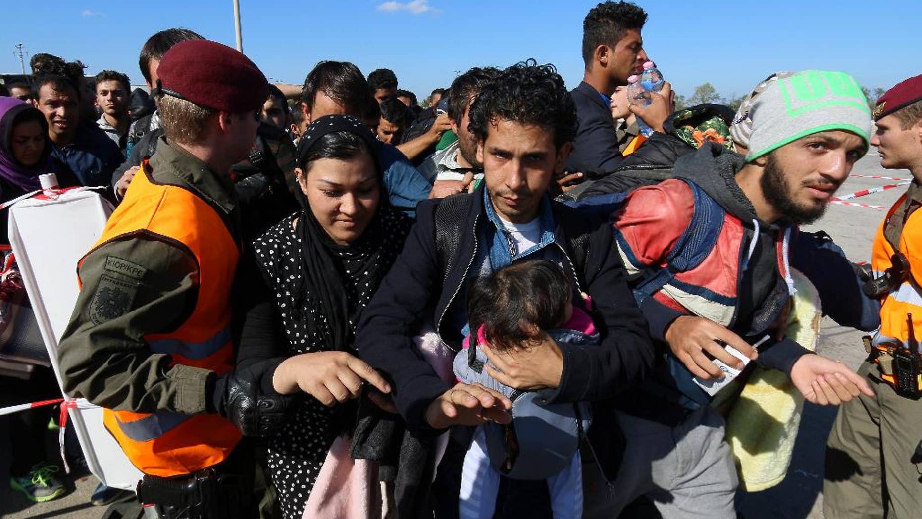 Migrants wait for buses after crossing the border between Hungary and Austria in Nickelsdorf, Austria, 70 kilometers (43 miles) southeast of Vienna, Thursday, Oct. 1, 2015. The European Union is threatening to take action against Hungary over laws it has introduced to limit the flow of migrants through its territory. (AP Photo/Ronald Zak)