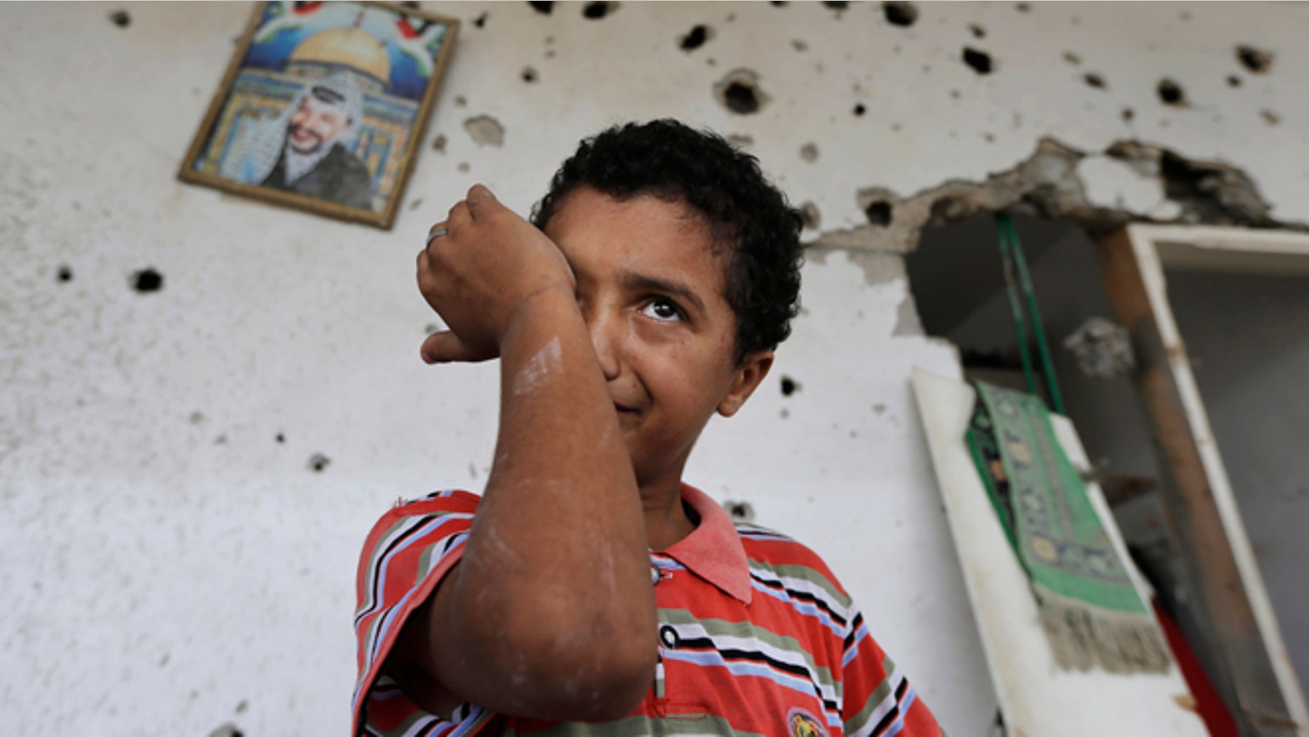Backdropped by a picture of late Palestinian leader Yasser Arafat, Palestinian Anas Shabat, 10, weeps as he inspects damages upon returning to his family house, destroyed by Israeli strikes in the town of Beit Hanoun, northern Gaza Strip, Tuesday, Aug. 5, 2014. Israel and Hamas began observing a temporary cease-fire on Tuesday that sets the stage for talks in Egypt on a broader deal on the Gaza Strip, including a sustainable truce and the rebuilding of the battered, blockaded coastal territory. (AP Photo/Lefteris Pitarakis)