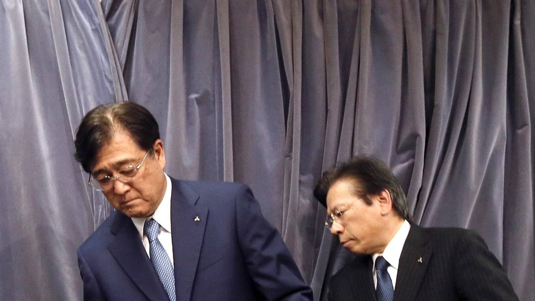 FILE - In this May 11, 2016 photo, Mitsubishi Motors Corp. Chairman and CEO Osamu Masuko, left, and President Tetsuro Aikawa prepare for their press conference in Tokyo. Mitsubishi Motors Corp., which recently acknowledged it inflated mileage for its models, is forecasting a 145 billion yen ($1.4 billion) loss for the fiscal year through March 2017. The Japanese automaker said Wednesday, June 22, vehicle sales will drop around the world, especially in Japan, where it expects a 41 percent plunge. The projected loss is a reversal from the 72.6 billion yen profit for the fiscal year ended March. (AP Photo/Eugene Hoshiko, File)