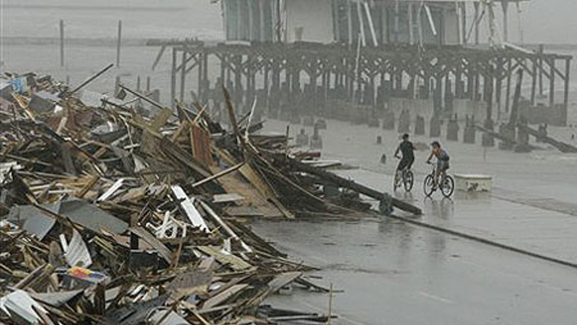 Sept. 14: Cyclists ride past debris piled up on the seawall road after Hurricane Ike hit the Texas coast.
