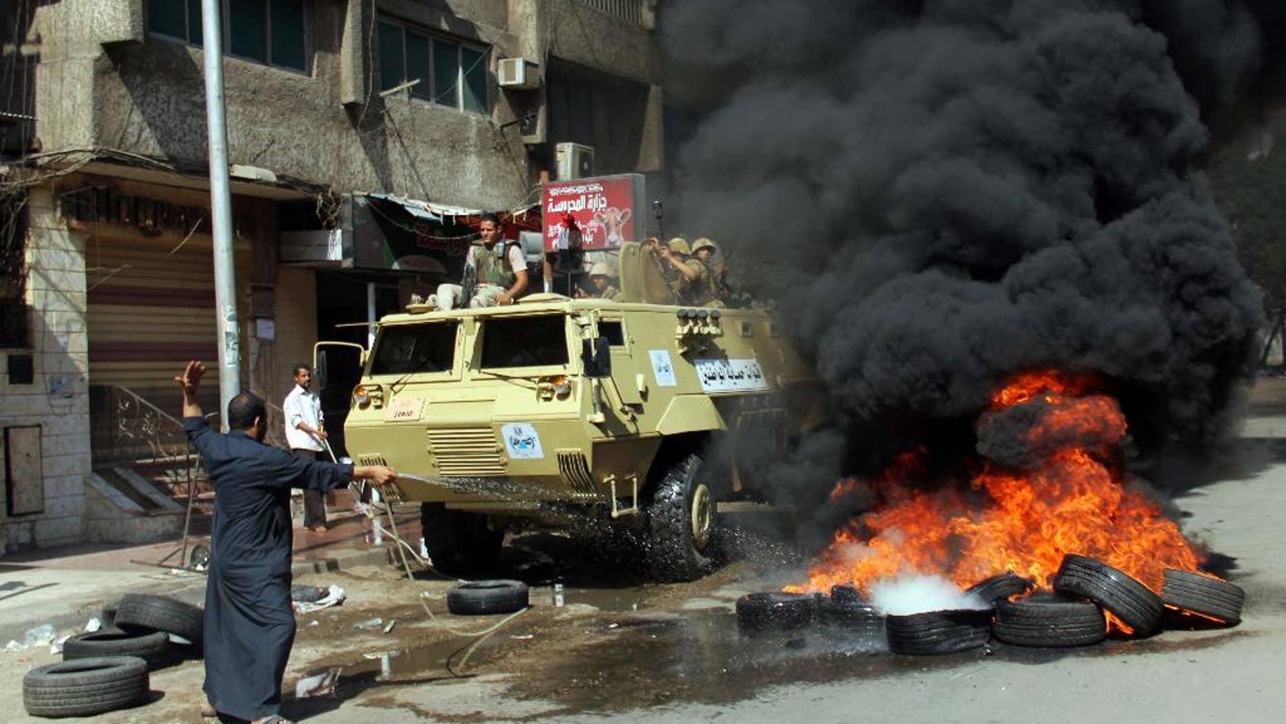 A man tries to extinguish burning tires set on fire during clashes between the security forces and supporters of the Muslim Brotherhood outside Al-Azhar University in Cairo, Egypt, Friday, May 23, 2014. Two protesters were killed in clashes in Egypt between Islamist demonstrators and their opponents after midday prayers Friday, the final day of campaigning ahead of next week's presidential election, authorities said. (AP Photo/Ahmed Taranh)