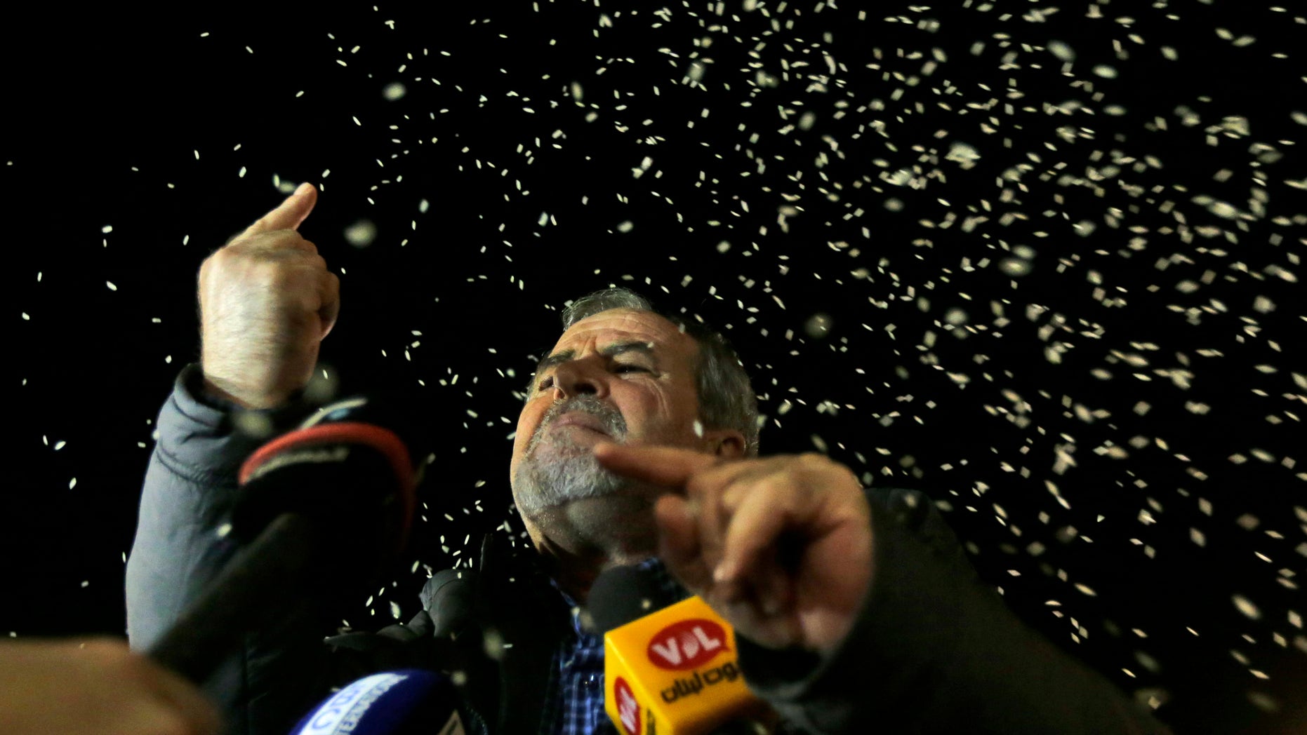 ADDS NAME - Ali Zougheib, one of the nine Lebanese Shiite pilgrims who were kidnapped by a rebel faction in northern Syria in May 2012, reacts as rice is seen throw over him, upon his arrival at Rafik Hariri international airport, in Beirut, Lebanon, Saturday, Oct. 19, 2013. Two Turkish pilots held hostage in Lebanon and nine Lebanese pilgrims abducted in Syria returned home Saturday night, part of an ambitious three-way deal cutting across the Syrian civil war.(AP Photo/Hussein Malla)