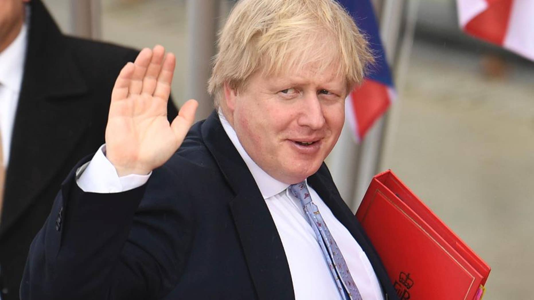 British Foreign Secretary Boris Johnson waves as he arrives for a meeting.