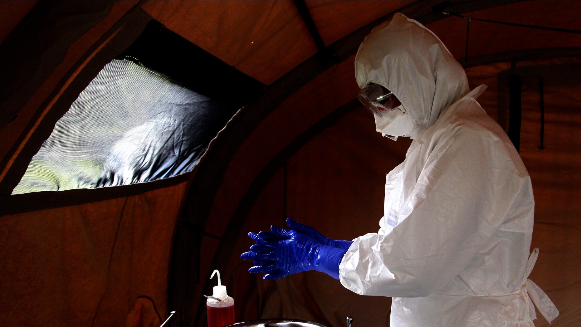FILE - In this Sept. 24, 201, file photo, nurse Dalila Martinez, trainer of the Cuban medical team to travel to Sierra Leone, washes her gloved hands during a practice drill at a training camp, in Havana, Cuba. Cuba's health ministry is sending more than 160 health workers to help stop the raging Ebola outbreak in Sierra Leone in early October. Cuba says a member of the 165-member medical team it sent to fight Ebola in Sierra Leone has been diagnosed with the disease. (AP Photo/Ladyrene Perez, Cubadebate,File)