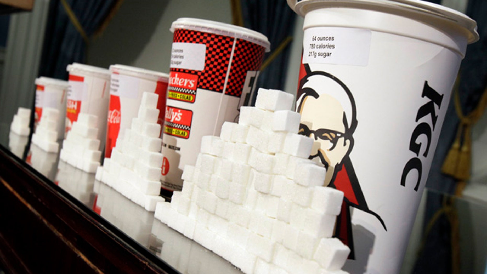 Various size cups and sugar cubes are displayed at a news conference at New York's City Hall, Thursday, May 31, 2012. New York Mayor Michael Bloomberg is proposing a ban on the sale of large sodas and other sugary drinks in the city's restaurants, delis and movie theaters in the hopes of combating obesity, an expansion of his administration's efforts to encourage healthy behavior by limiting residents' choices. (AP Photo/Richard Drew)