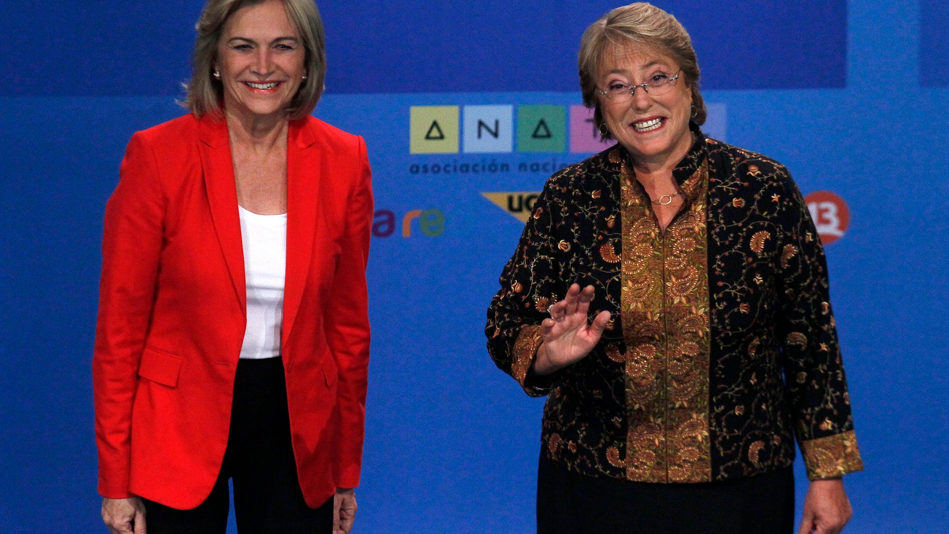 In this Tuesday, Dec. 10, 2013 photo, Chile's presidential candidate Michelle Bachelet, right, and rival Evelyn Matthei, smile for photographers before their television debate in Santiago, Chile. Bachelet and Matthei were childhood friends, but found themselves on opposite sides of the deep political divide after Chile's bloody 1973 military coup. Bachelet, who became Chile's first women president from 2006-2010, is now expected to retake the presidency in the Dec. 15 run-off election. (AP Photo/ Luis Hidalgo)