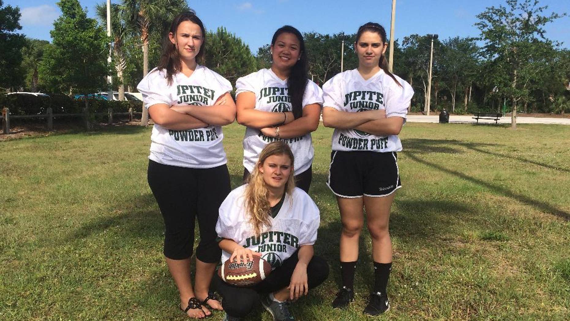 In this photo taken Monday, May 2, 2016, Jupiter High powderpuff football players Caitlin Walsh, Megan Mendoza, Haley Osborne and Savannah Tardonia, in front with ball, pose for a group photo in Jupiter, Fla. The clock has run out on what boosters describe as the nation's last tackle powderpuff football game. For 50 years at Jupiter High School, school spirits have been stoked by the annual football game pitting senior girls against juniors in a true test of toughness. But safety concerns prompted the principal to cancel this year's game, and many people in the middle-class suburb on the Palm Beach coast feel blindsided. (AP Photo/Terry Spencer)